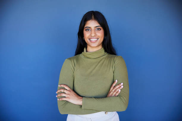indian girl 3 Portrait of a smiling young businesswoman standing with her arms crossed in front of a blue wall in an office